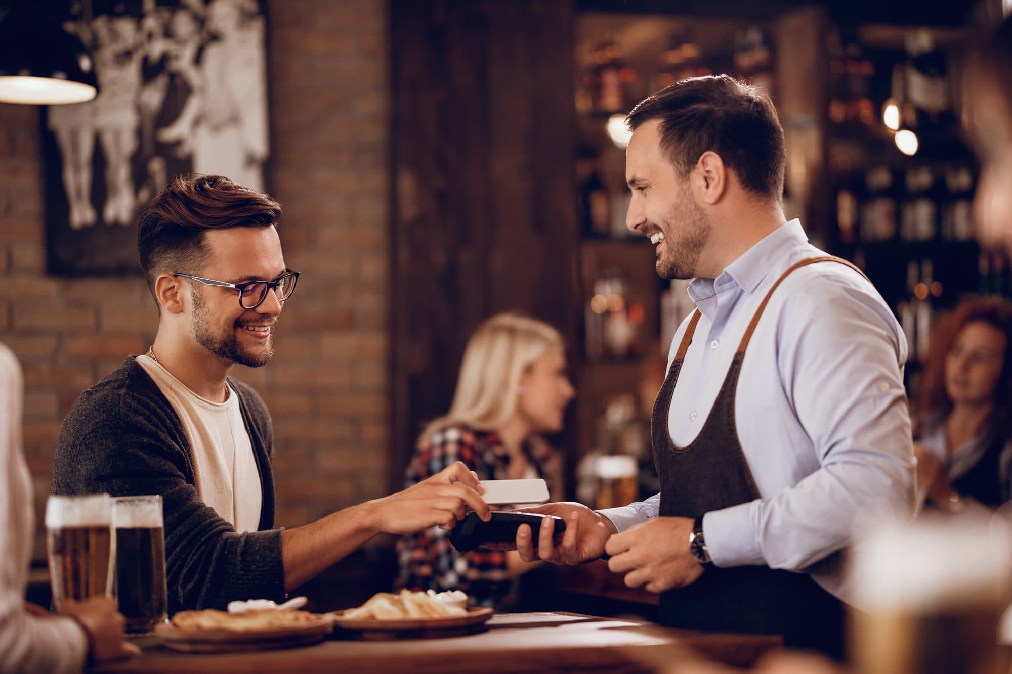 Gast zahlt kontaktlos an der Bar – zufriedener Service
